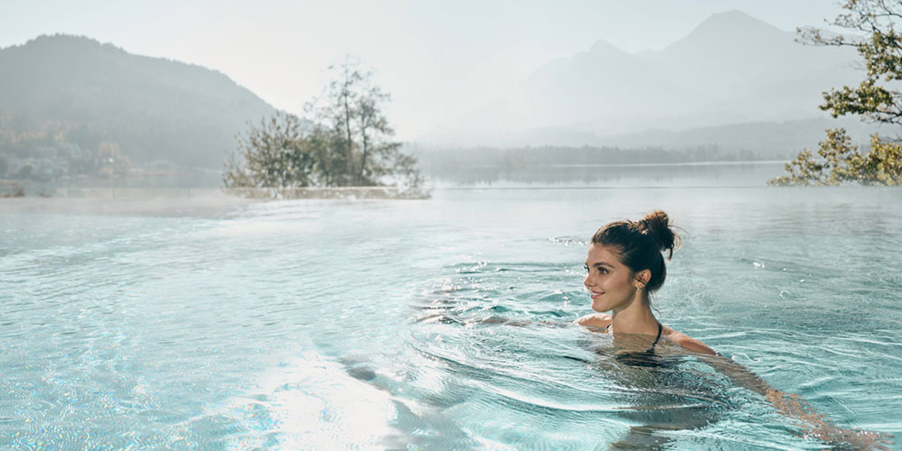Frau schwimmt im Außenpool des Hotels Karnerhof in den Alpen