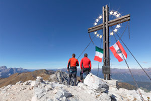 Zwei Männer stehen auf dem Europakreuz auf der Großen Kinigat in den Sextener Dolomiten 