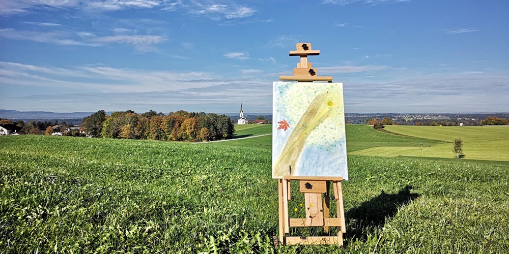 Staffelei mit selbstgemalten Bild in Landschaft im Allgäu